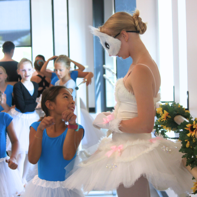 A young dancer admiring the older ballerina, wearing a white cat costume