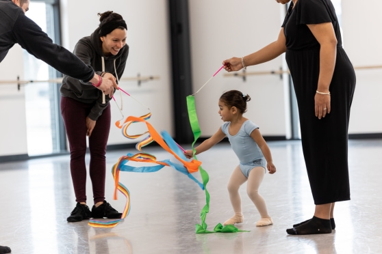 a group of people holding ribbons and a child plays with them in the studio.