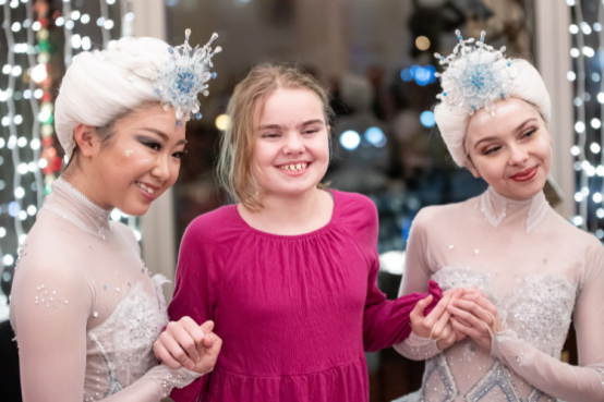 Young girl poses with two dancers in costume.
