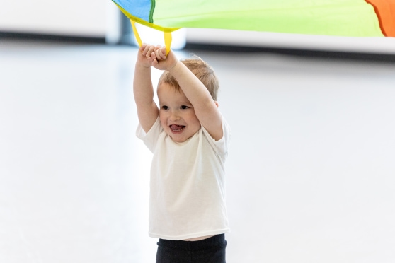 a toddler enjoying some parachute time in class