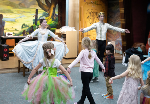Two instructors in costume leading young girls in ballet.