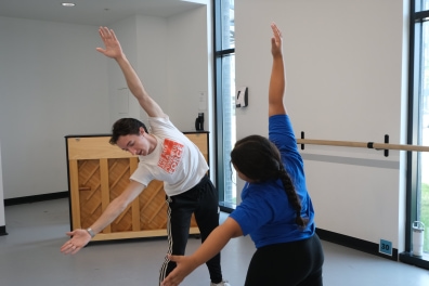 Girl is taught by instructor on stretches.