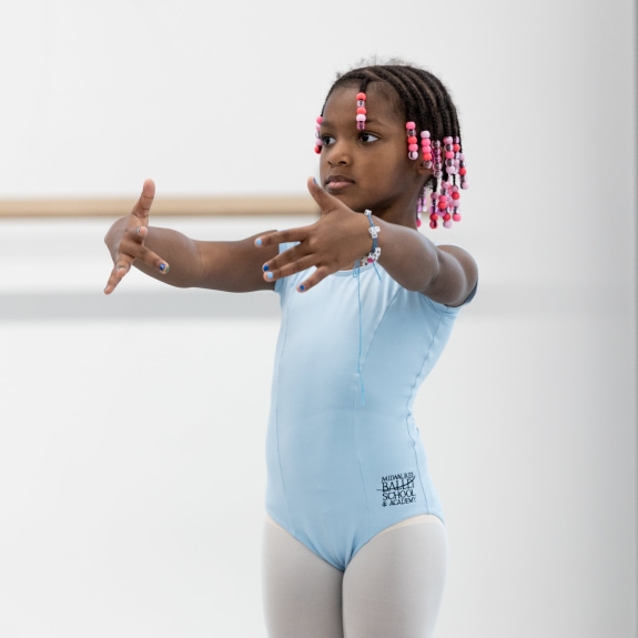a child wearing ballet clothes and standing in first position