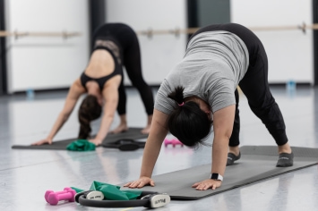 adult dance and fitness pilates participants stretch on mats.