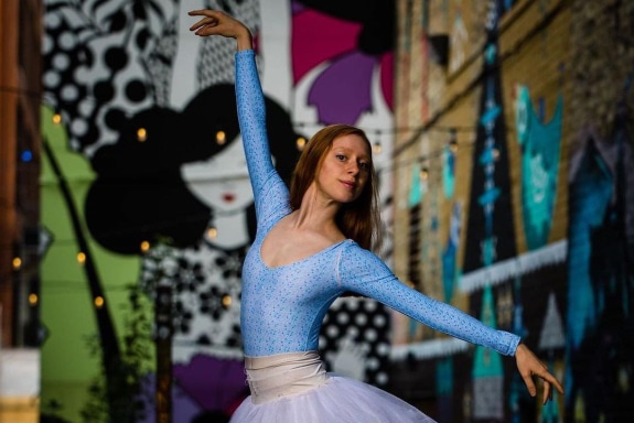 Daniela Maaraoui poses in Black Cat Ally, while wearing a blue leotard, white tutu, and pointe shoes