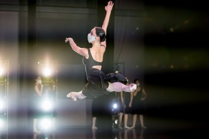 a person in a black dress and white mask jumping in the air